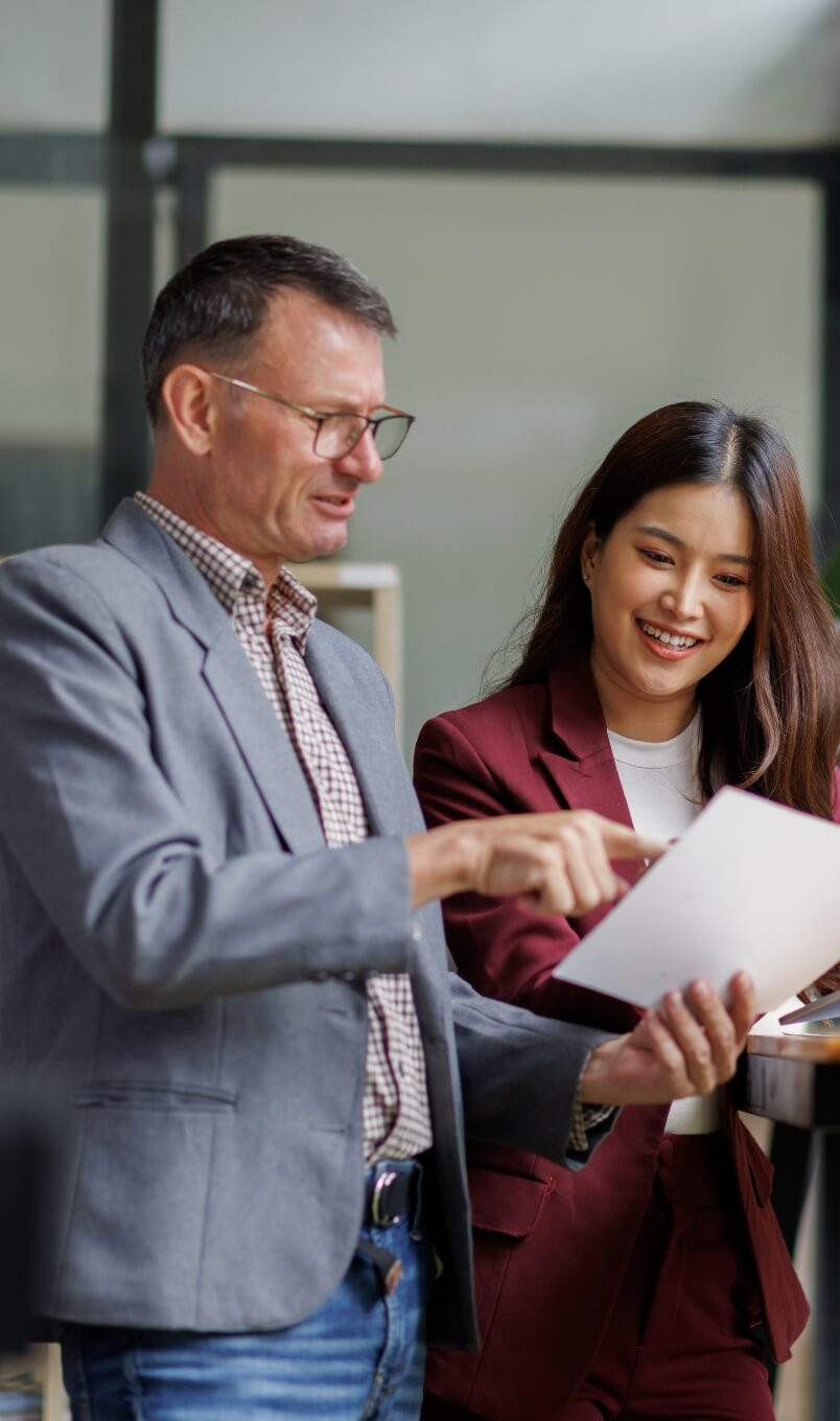 Two professionals reviewing documents together in a modern office setting