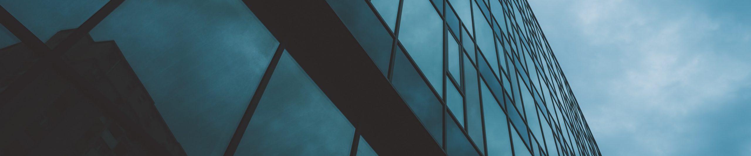 Modern glass building facade against blue sky, representing corporate advisory services