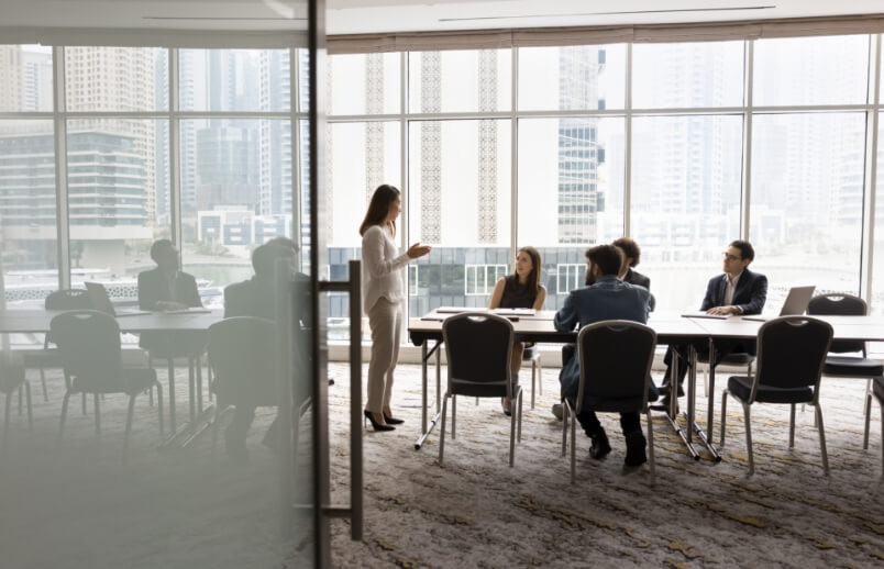 Team of professionals in a high-rise office meeting room with city skyline views through floor-to-ceiling windows