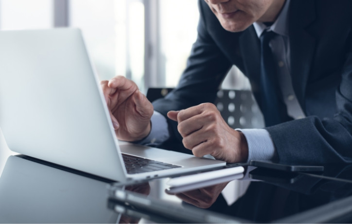 Professional businessman reviewing financial data on laptop and tablet at desk
