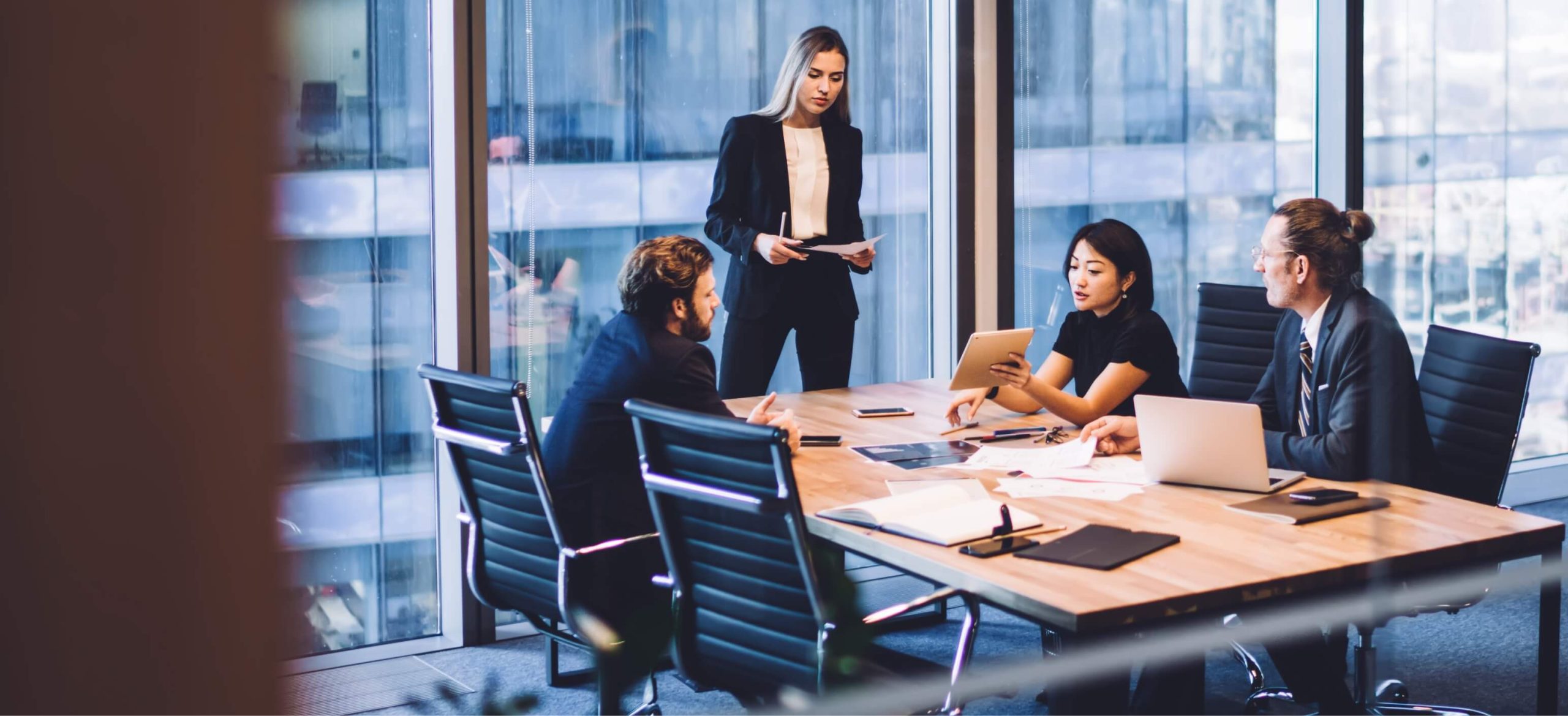Professional team meeting in modern high-rise office with city skyline view during business discussion