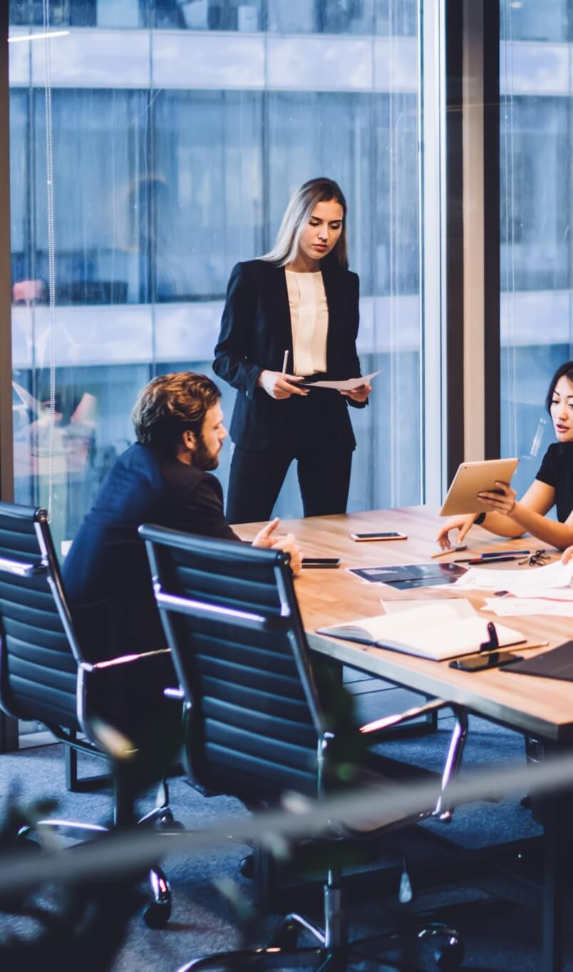 Business professionals in a modern office meeting room discussing strategy with documents and tablets