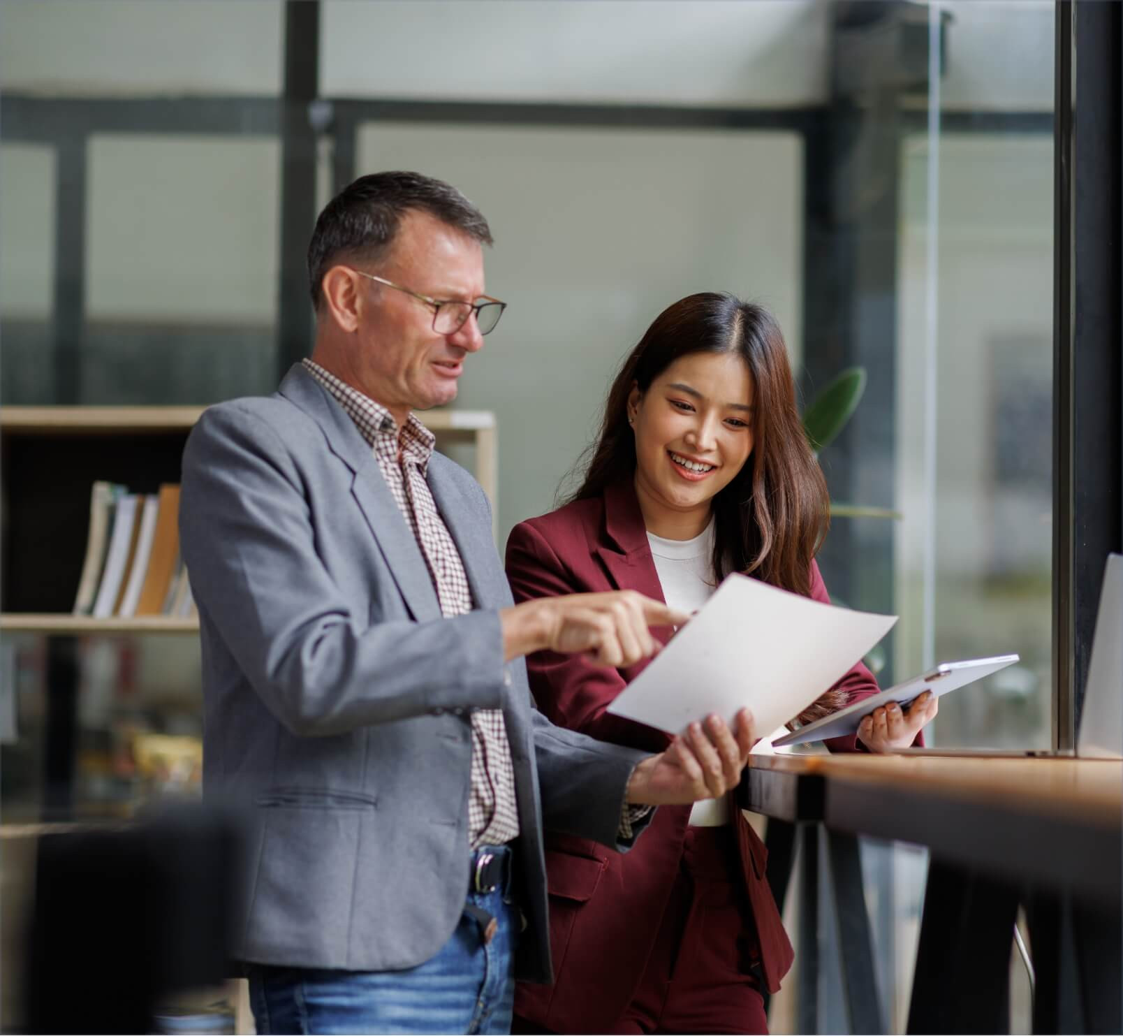 Two professionals reviewing a document together in a modern office with glass partitions