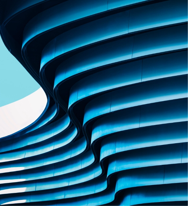 Modern blue architectural building with illuminated curved horizontal bands against clear sky
