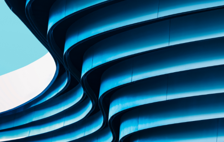 Modern spiral architecture with blue-lit curved bands against clear sky, representing innovation and structure