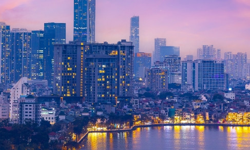 Hanoi skyline at dusk with illuminated buildings reflected in water below