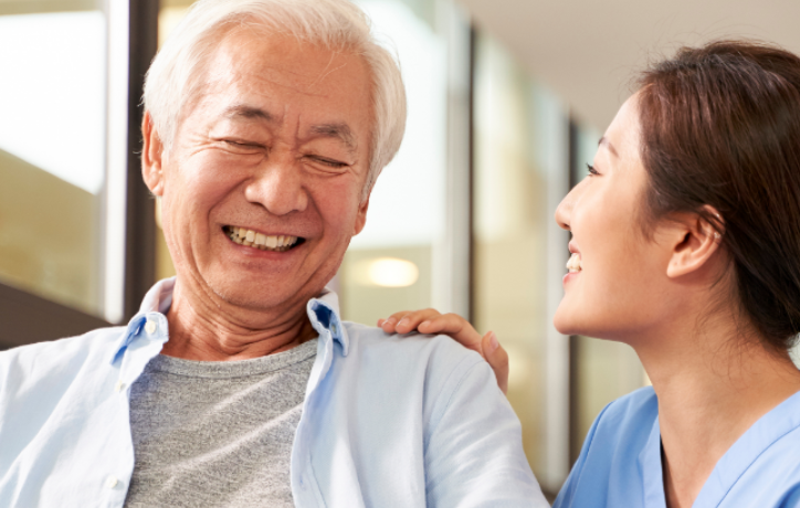 Senior man and healthcare professional smiling together in a medical facility corridor