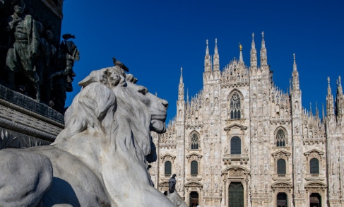 Lion statue with Milan Cathedral's Gothic spires in background