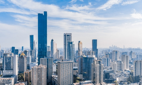 Urban skyline with tall residential and commercial buildings under blue sky with clouds