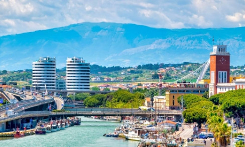 Pescara cityscape with modern buildings, bridge, waterfront and mountains in background
