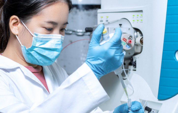 Laboratory technician in protective gear operating pharmaceutical testing equipment in a clinical setting