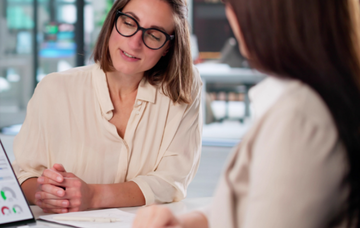 Professional woman in glasses smiling during a business consultation with a client in a modern office setting