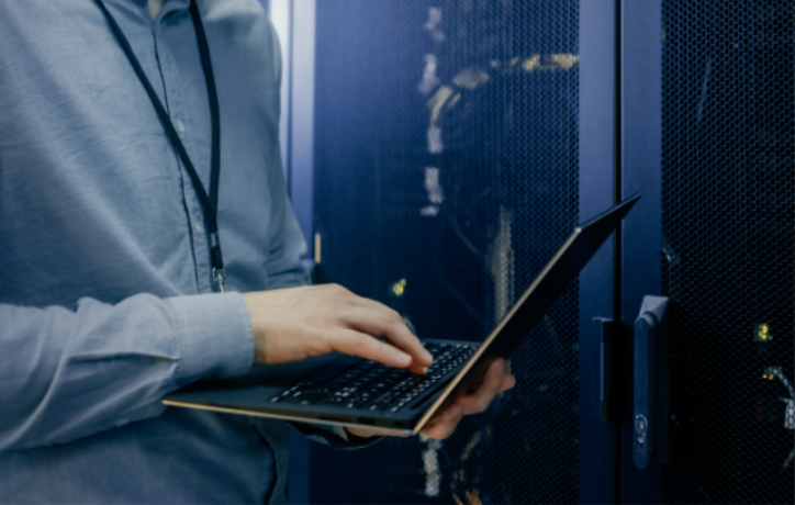 IT professional working on laptop in server room with data center infrastructure