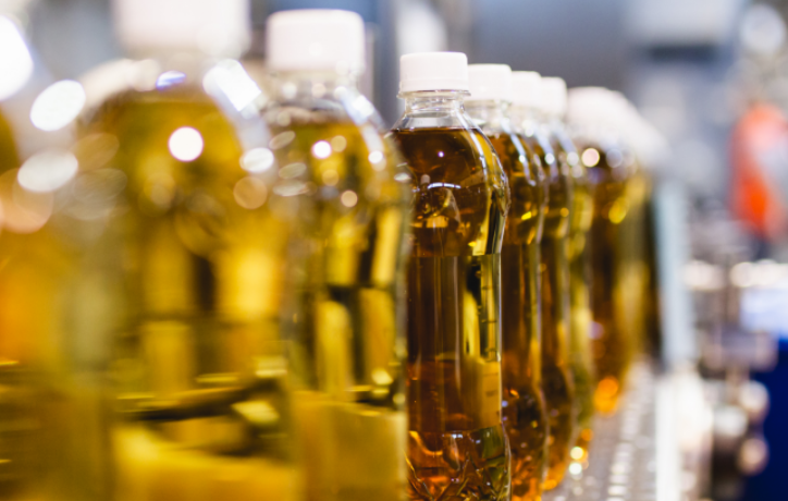 Row of bottles with golden-yellow oil or liquid, representing food and beverage production and supply
